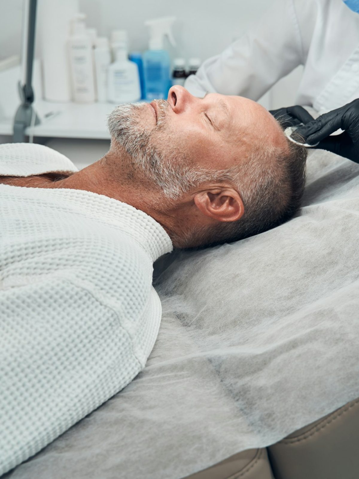 Man receiving hair loss treatment in cosmetology clinic Guía completa del injerto capilar: Qué esperar antes, durante y después del tratamiento - Uve Medical, clinica de estetica facial y capilar